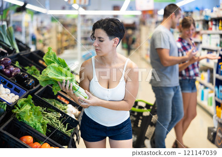 Woman choosing lettuce in supermarket 121147039