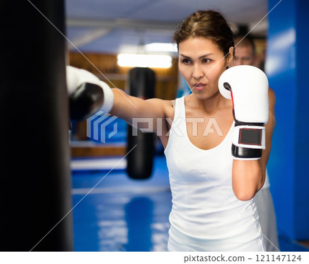 Asian woman training with punchbag 121147124
