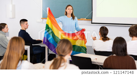 Adult female teacher showing LGBT flag to students Adult female teacher showing LGBT flag to students 121147148