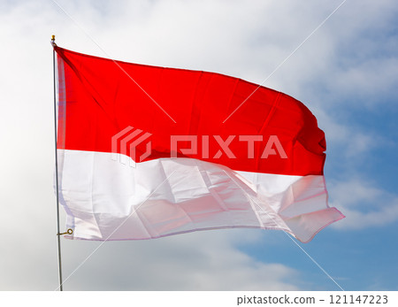 Against background of cloudy sky, white-red Monegasque flag flutters on flagpole Against background of cloudy sky, white-red Monegasque flag flutters on flagpole 121147223
