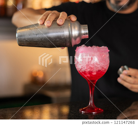 Bartender serving tequila sunrise cocktail at bar 121147268
