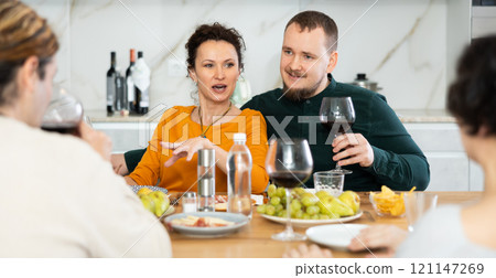 Two married couples are sitting at table, enjoying food and wine, chatting, talking, laughing. Two married couples are sitting at table, enjoying food and wine, chatting, talking, laughing. 121147269