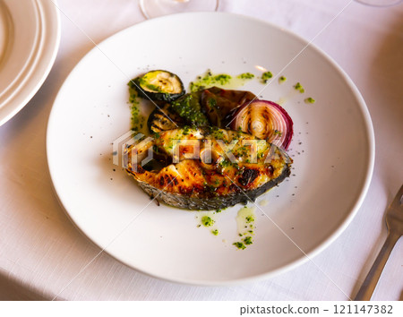 Grilled corvina steak with vegetables and herb sauce 121147382