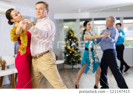 Couples dancing during Christmas - men and women dancing tango or samba next to Christmas tree 121147415