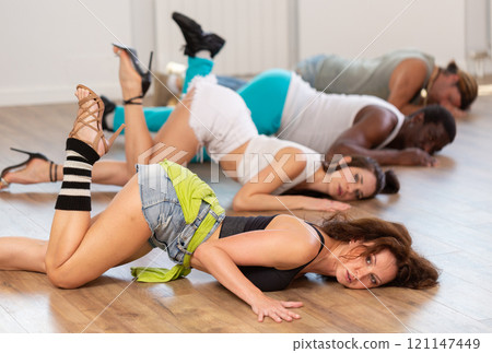 Slender dancers on the floor while dancing in high heels in the studio, performing sensual moves in dance studio Slender dancers on the floor while dancing in high heels in the studio, performing sensual moves in dance studio 121147449