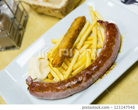 Rustic sausage with fried potato served at plate with sauce 121147548