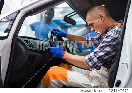 Serviceman making car diagnostics in a workshop Serviceman making car diagnostics in a workshop 121147675