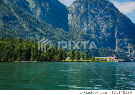 Konigssee Lake in Bavaria Germany with Church by the Lake White Boat Forested Mountain and Beautiful Sunny Trekking in Berchtesgaden German Alps. High quality photo Konigssee Lake in Bavaria Germany with Church by the Lake White Boat Forested Mountain and Beautiful Sunny Trekking in Berchtesgaden German Alps. High quality photo 121148189