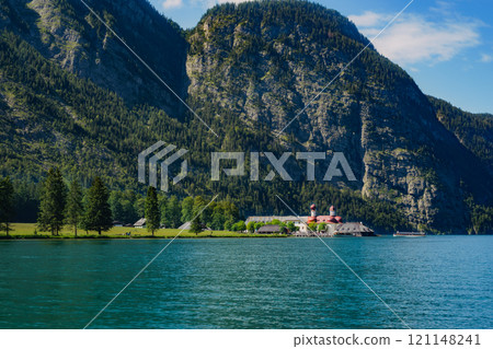Konigssee Lake in Bavaria Germany with Church by the Lake White Boat Forested Mountain and Beautiful Sunny Trekking in Berchtesgaden German Alps. High quality photo Konigssee Lake in Bavaria Germany with Church by the Lake White Boat Forested Mountain and Beautiful Sunny Trekking in Berchtesgaden German Alps. High quality photo 121148241