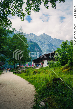 Wood house by the mountain Konigssee Lake in Bavaria Germany with Church by the Lake White Boat Forested Mountain and Beautiful Sunny Trekking in Berchtesgaden German Alps. High quality photo Wood house by the mountain Konigssee Lake in Bavaria Germany with Church by the Lake White Boat Forested Mountain and Beautiful Sunny Trekking in Berchtesgaden German Alps. High quality photo 121148245