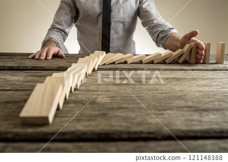 Businessman hand stopping domino effect Businessman hand stopping domino effect 121148388