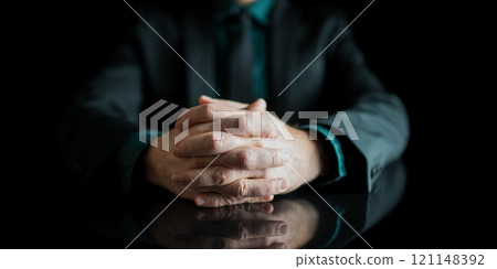 Businessman hands joined together resting on black desk with reflection Businessman hands joined together resting on black desk with reflection 121148392