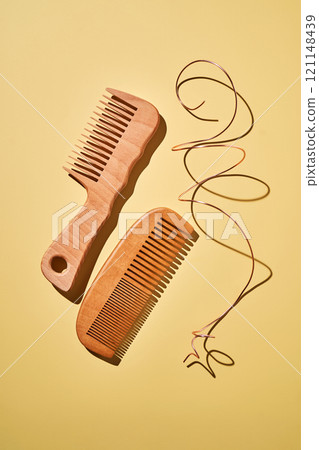 Two wooden combs on a yellow background. 121148439