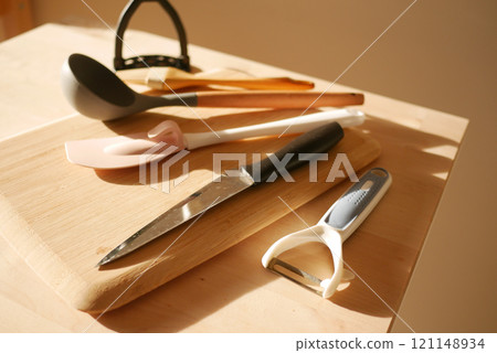 A Variety of Colorful Kitchen Utensils Arranged on a Wooden Cutting Board A Variety of Colorful Kitchen Utensils Arranged on a Wooden Cutting Board 121148934
