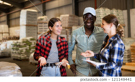 Workers and manager discussing completed work in large warehouse Workers and manager discussing completed work in large warehouse 121149441
