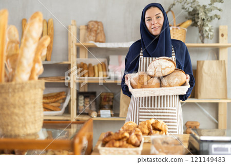 Portrait of girl seller of oriental bakery in traditional Muslim clothes with of baguettes 121149483