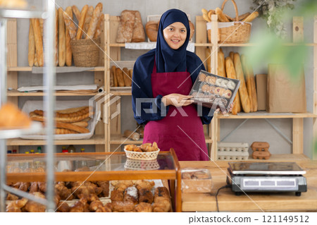Saleswoman with a box of cookies in a supermarket Saleswoman with a box of cookies in a supermarket 121149512