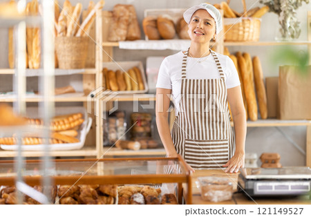 Uniformed saleswoman stands behind the counter Uniformed saleswoman stands behind the counter 121149527