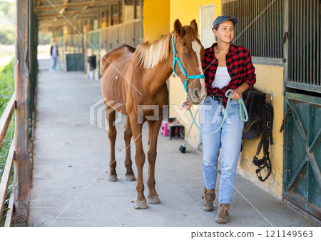 Young woman leads horse out of stable Young woman leads horse out of stable 121149563