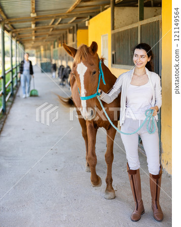Young woman leads horse out of stable Young woman leads horse out of stable 121149564