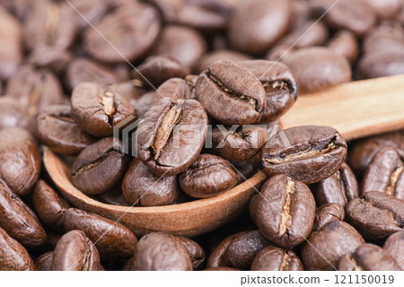 Spoon with coffee beans on a coffee background. 121150019