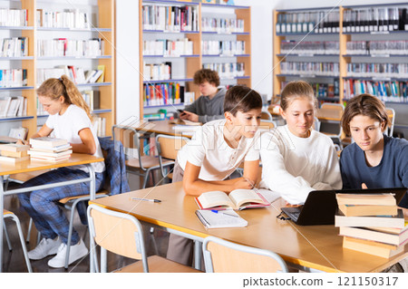 Group of schoolchildren reading books together in library and preparing for school exam 121150317