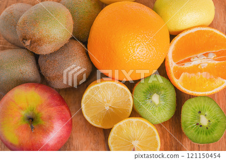 Fruits oranges, kiwi, apple, lemon on a wooden board. Healthy food. 121150454