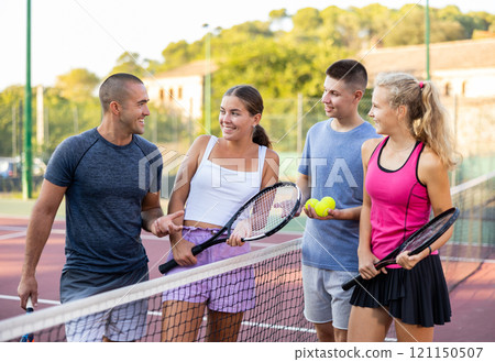 Two pairs of tennis players are happily discussing past game on an open court 121150507