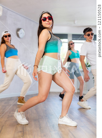 Expressive Hispanic teenage girl dancing hip-hop with group in studio 121150528