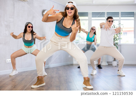 Group of young girls in dark glasses and ball cap and guy dance jazz-funk in fitness club. Group of young girls in dark glasses and ball cap and guy dance jazz-funk in fitness club. 121150530