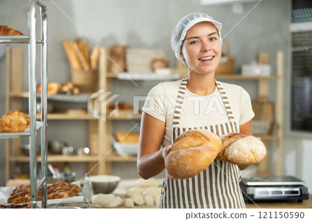 Young woman are standing in kitchen with finished products two loaves of rye bread 121150590