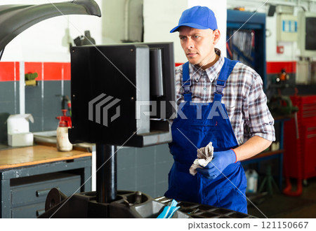 Mechanic worker balancing tire with wheel balancing machinery Mechanic worker balancing tire with wheel balancing machinery 121150667