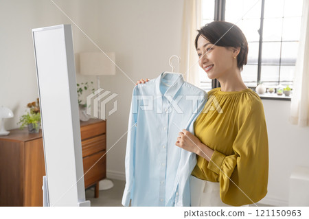A woman choosing clothes in a room 121150963