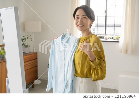 A woman choosing clothes in a room 121150964