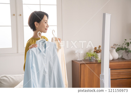 A woman choosing clothes in a room 121150973