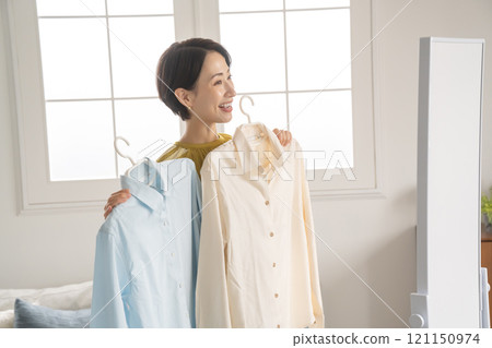 A woman choosing clothes in a room A woman choosing clothes in a room 121150974