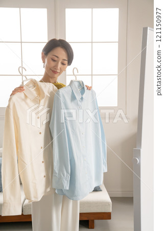 A woman choosing clothes in a room A woman choosing clothes in a room 121150977