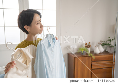 A woman choosing clothes in a room A woman choosing clothes in a room 121150980
