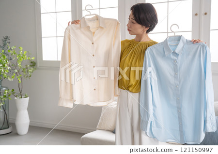A woman choosing clothes in a room 121150997