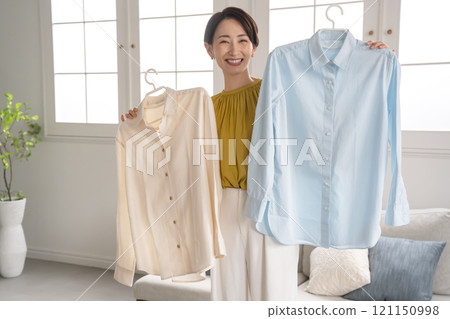 A woman choosing clothes in a room A woman choosing clothes in a room 121150998