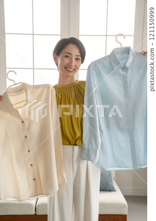 A woman choosing clothes in a room A woman choosing clothes in a room 121150999
