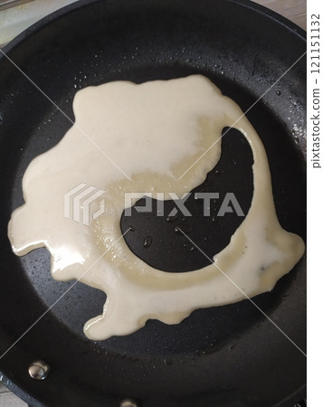 Unbaked batter for a pancake of a funny shape 121151132