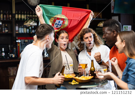Group of cheerful people cheering for favorite Portuguese sports team in pub Group of cheerful people cheering for favorite Portuguese sports team in pub 121151232