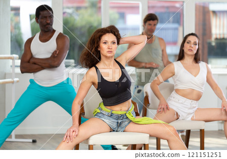 Dark-haired woman dancing on chair during sass dance class in studio Dark-haired woman dancing on chair during sass dance class in studio 121151251