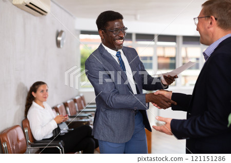 In office glad person makes deal, shaking hands with middle-aged African man colleague In office glad person makes deal, shaking hands with middle-aged African man colleague 121151286