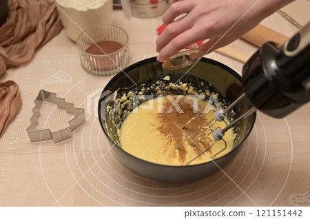 Christmas homemade baking, ingredients for baking gingerbread, woman adding spices to dough in black bowl 121151442