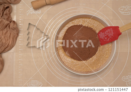Christmas homemade baking, ingredients for baking gingerbread, silicone spatula in a white bowl with cocoa and flour, tree shaped cutter and rolling pin 121151447