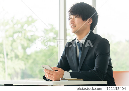 A young Asian businessman using smartphone apps 121152404