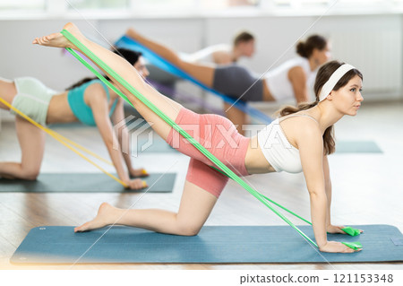 Young girl practicing back leg lift with band standing on knees 121153348