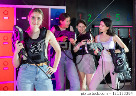 Cheerful and happy girl pose in locker room before laser tag match. Cheerful and happy girl pose in locker room before laser tag match. 121153394